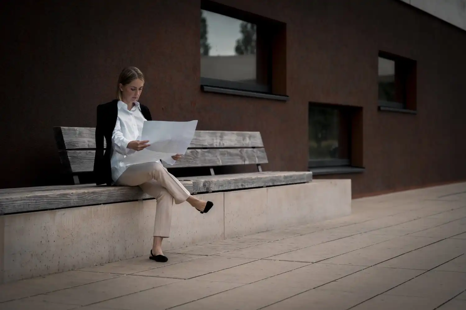 Vergin-Immobilien- Eine Frau sitzt auf einer Bank und liest ein Dokument.
